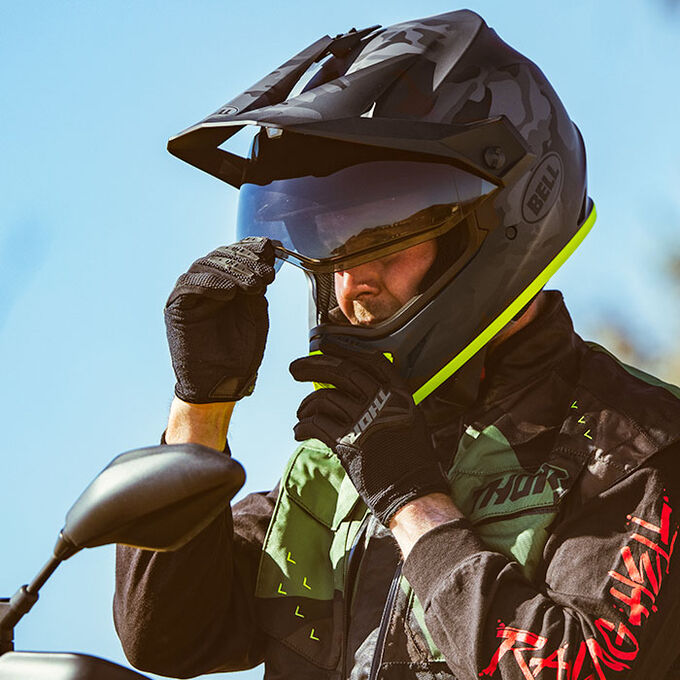 Rider adjusting goggles while wearing Bell MX-9 Adventure MIPS helmet