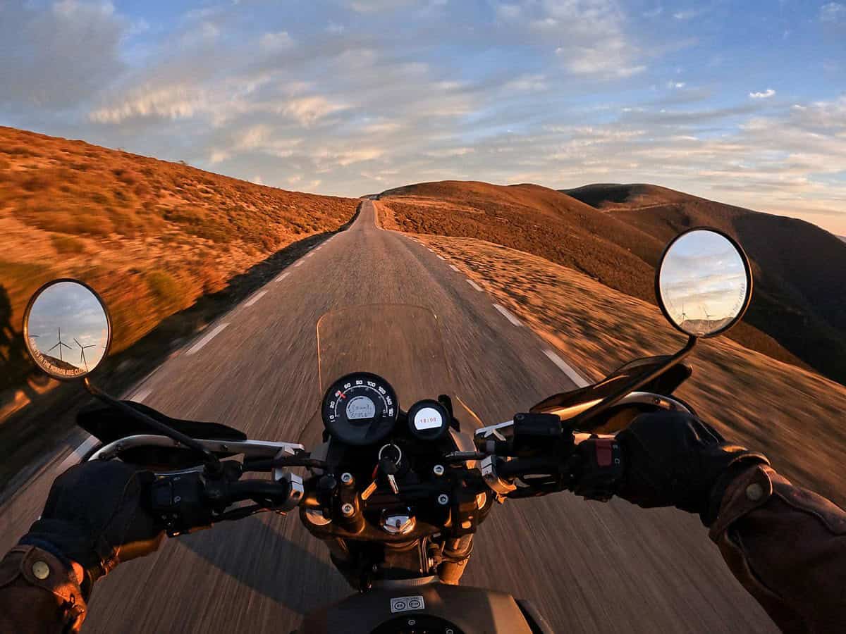 Rider on a scenic road during sunset, symbolizing adventure and dual-sport motorcycling versatility.