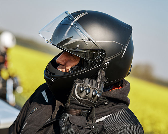Motorcyclist using a helmet with integrated Bluetooth speaker system on a scenic ride.