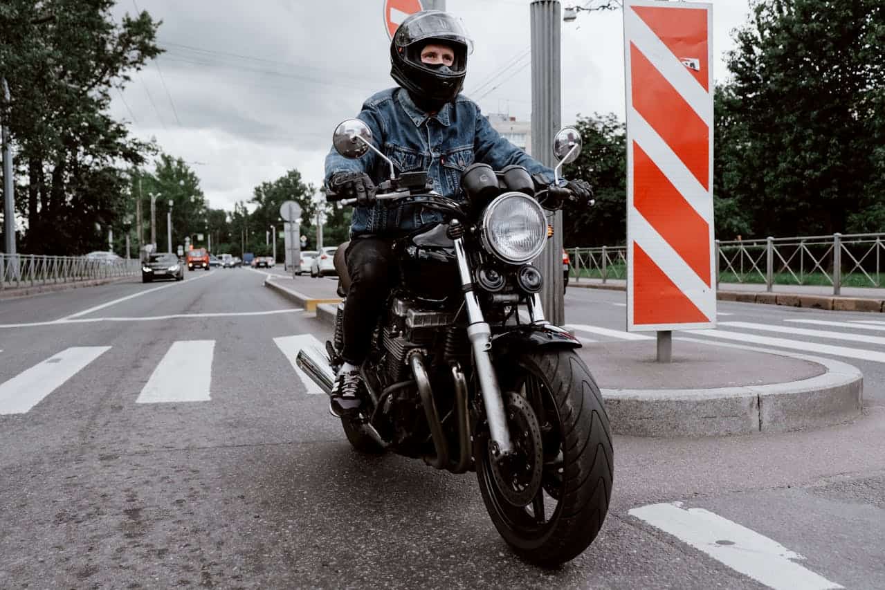 Motorcyclist in city traffic wearing casual gear on a black bike