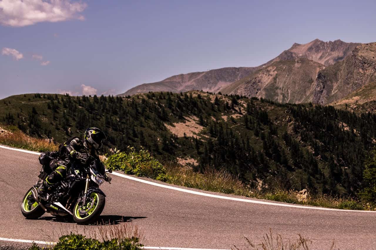 Motorcyclist leaning into a mountain pass curve under clear skies