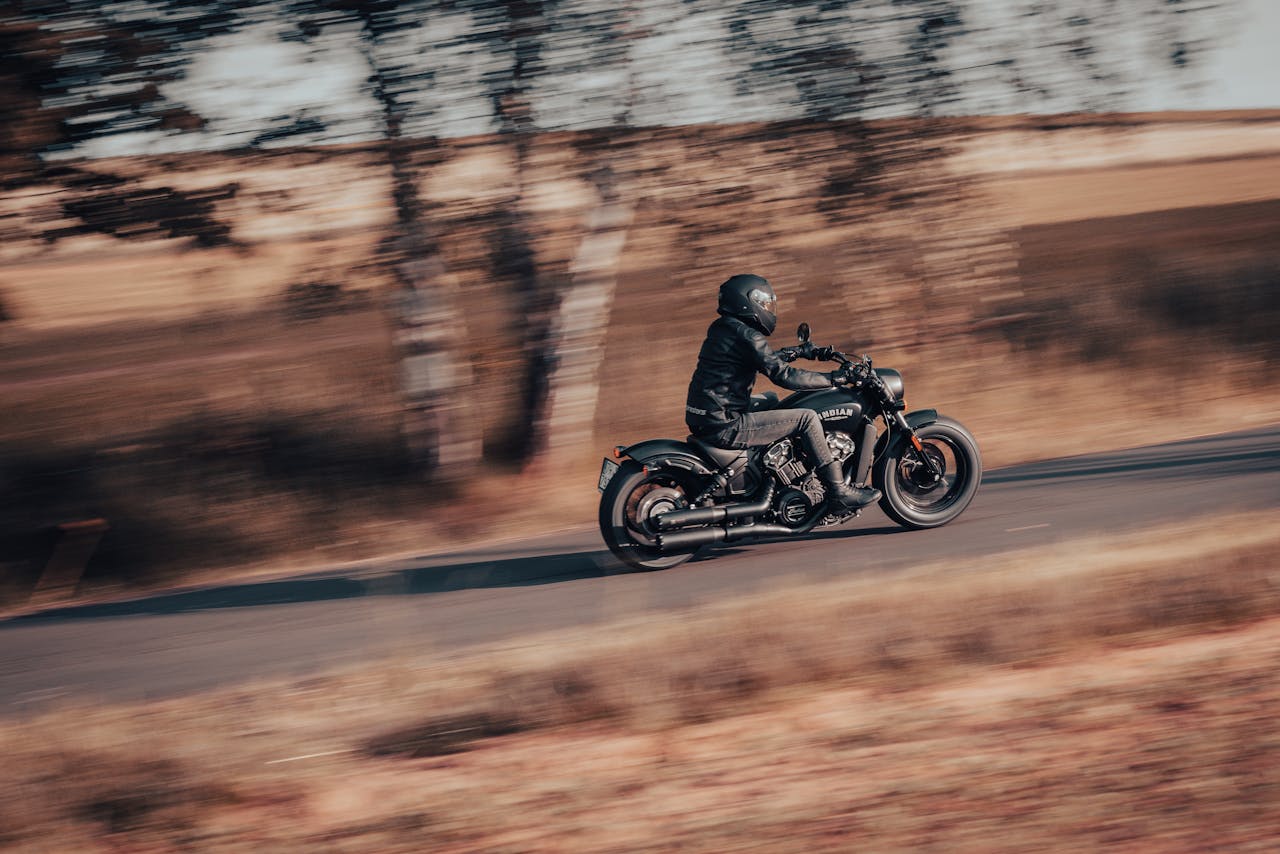 Motorcyclist in full gear riding at speed through a rural road