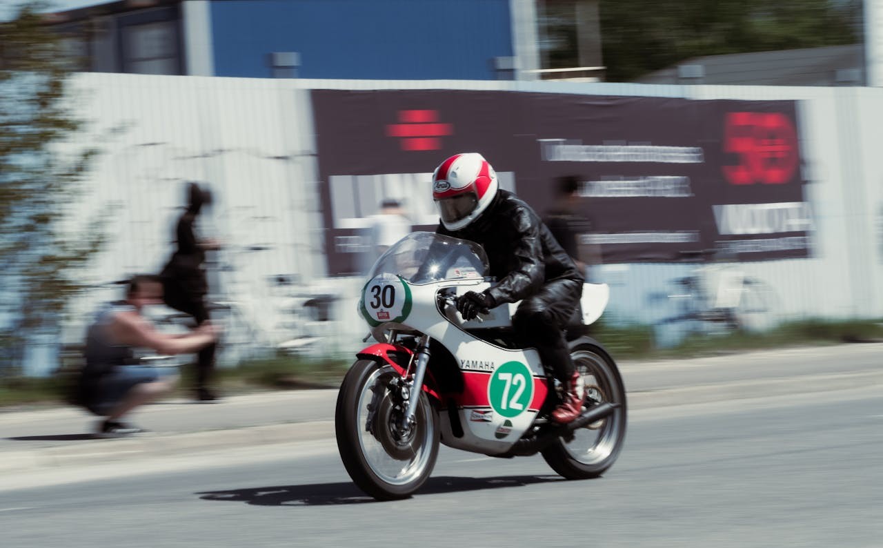 Motorcyclist in full gear racing on a vintage Yamaha bike at high speed