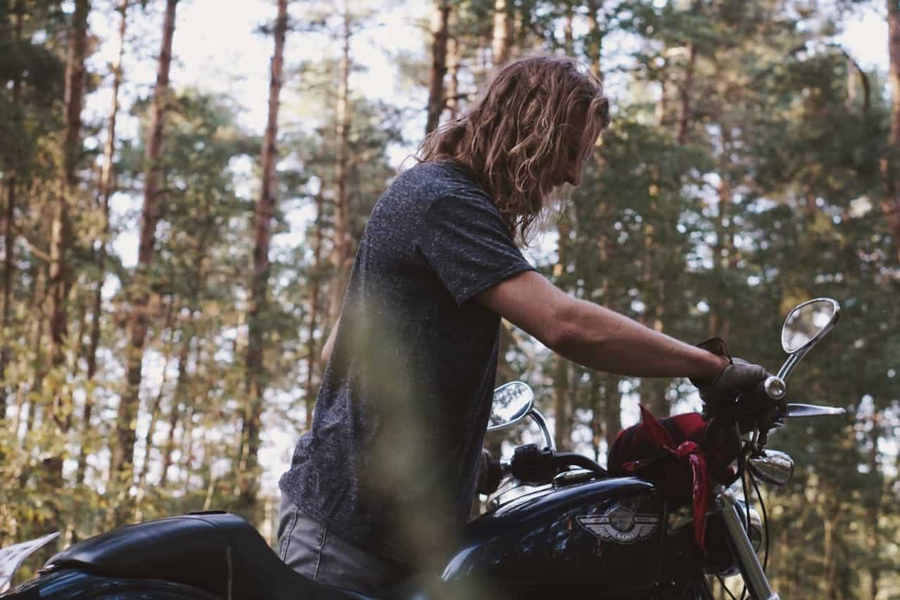 Motorcyclist adjusting handlebars during a quiet forest stop