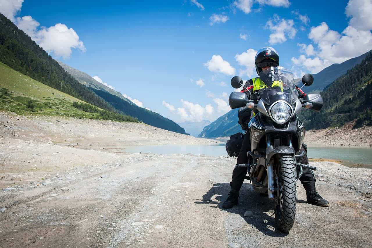 Motorcycle rider touring through mountain valley with minimalist gear setup