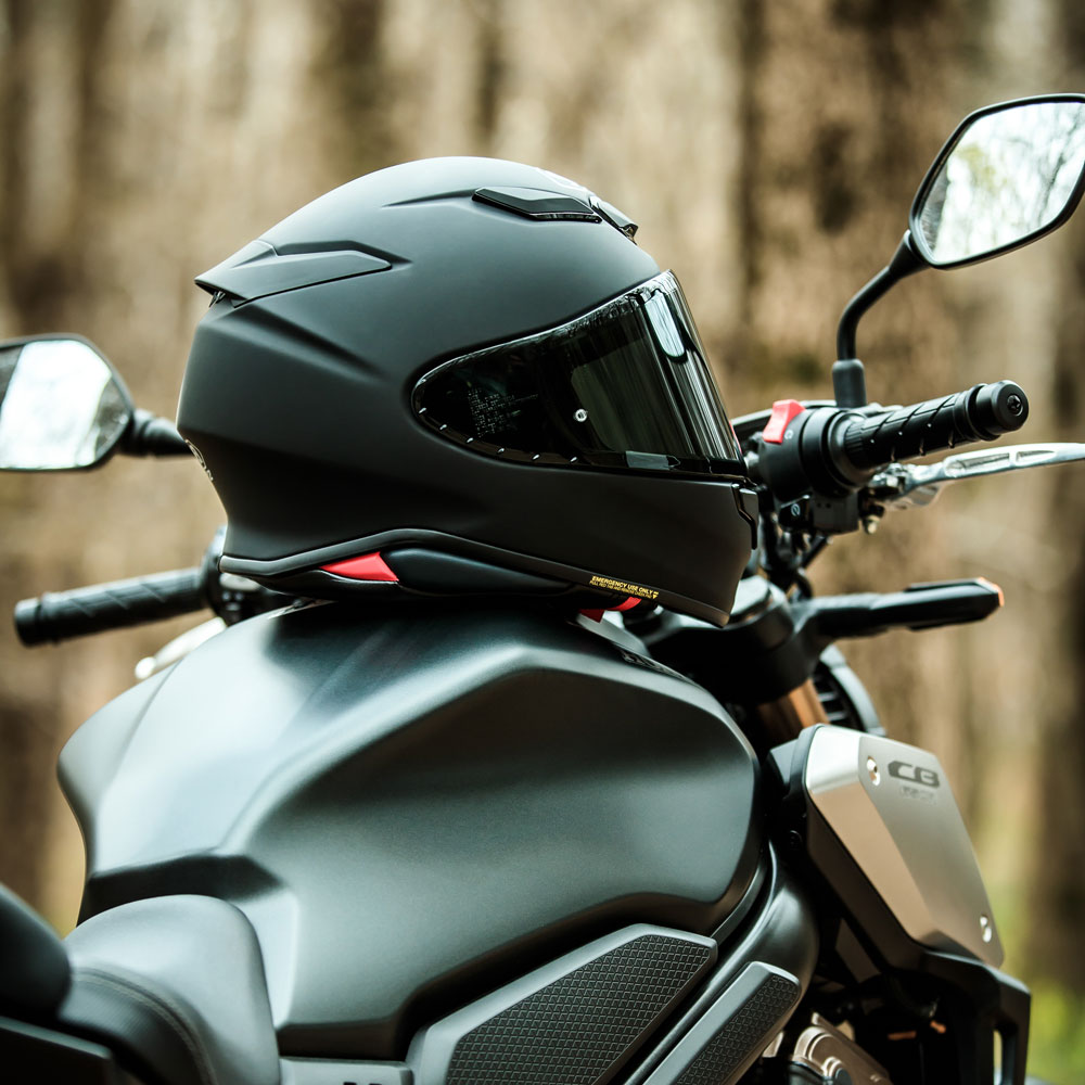 Shoei NXR2 full-face motorcycle helmet resting on a matte black bike
