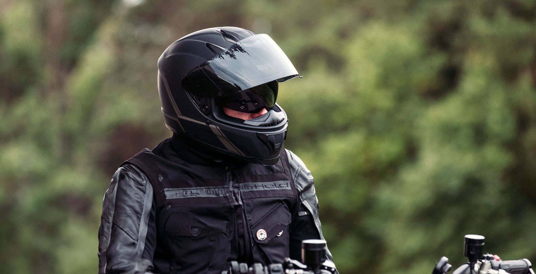 Motorcyclist wearing a matte black Sena Stryker helmet with face shield down