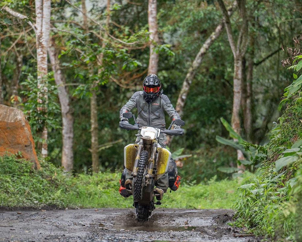 Rider standing on pegs wearing Klim Baja S4, showing pre-curved sleeves and flexible fit.