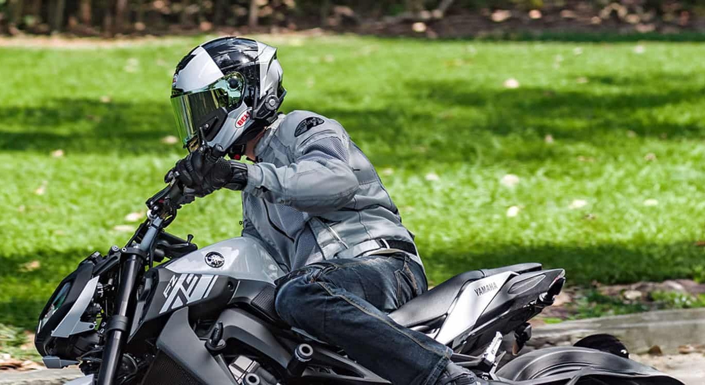 Rider on a Yamaha FZ wearing a Bell full-face helmet equipped with Sena 30K Bluetooth headset, cornering on a sunny day.
