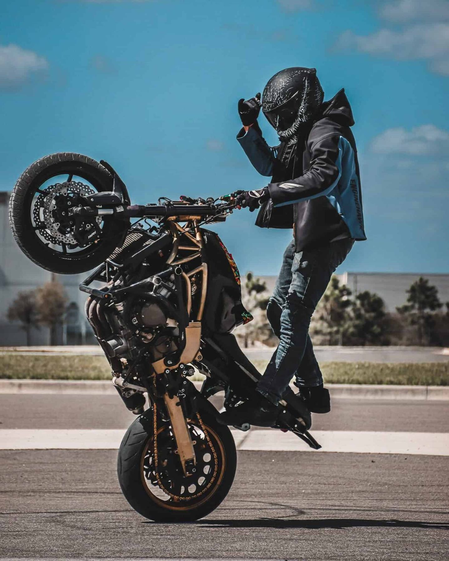 Rider performing a wheelie while wearing the Ruroc Atlas 4.0 Jormungandr helmet with bold symbiote-inspired graphics.