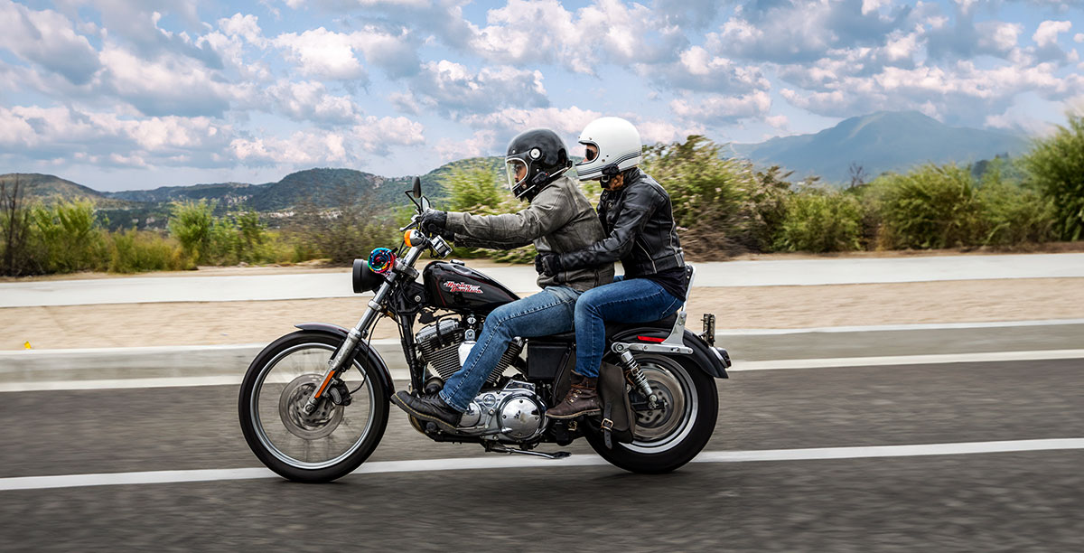 Two riders on a motorcycle wearing helmets with a Sena 5S Bluetooth headset in use.