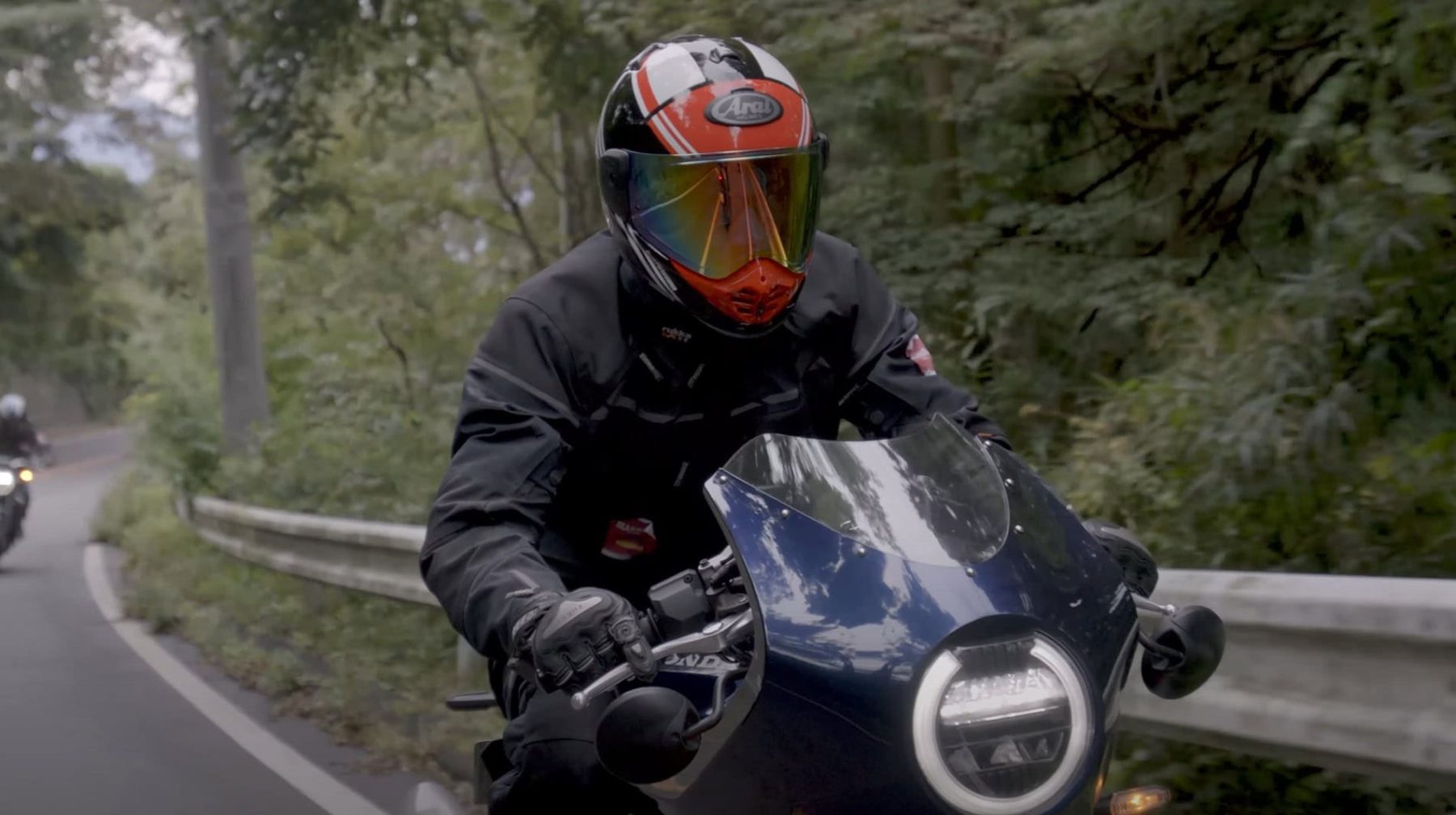 Motorcyclist wearing an Arai XD-5 helmet riding on a winding forest road