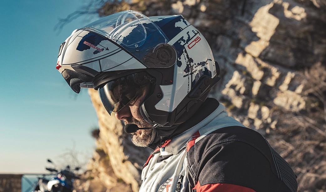 Touring rider wearing a Schuberth C5 helmet with chin bar raised, communicating through headset