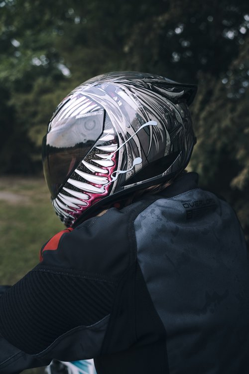 Rider wearing the Icon Domain Grand Maw helmet with stylized tooth and tongue graphic.