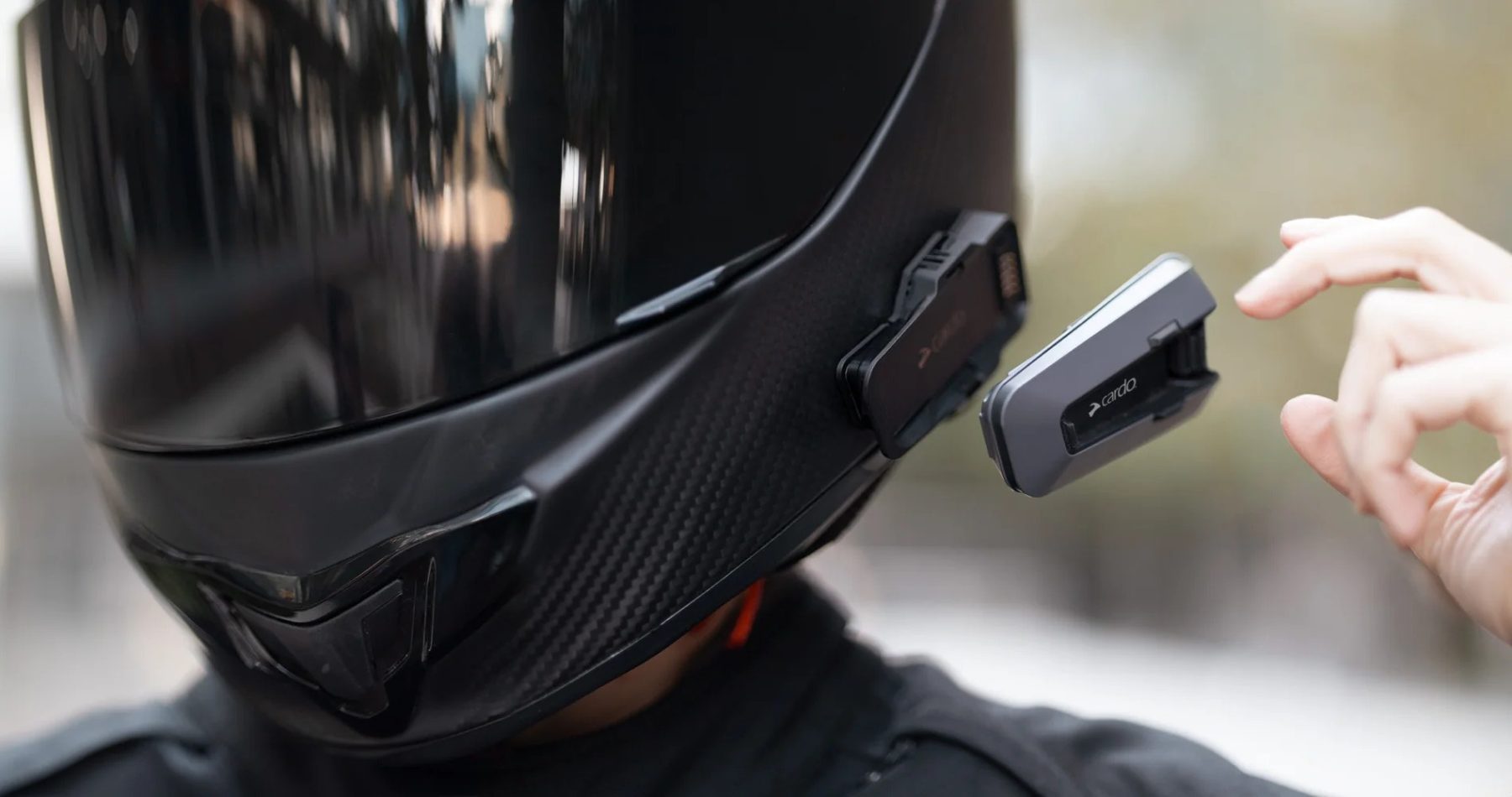 Motorcycle helmet with a rider attaching a Cardo Packtalk Edge using the magnetic Air Mount system.