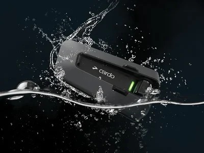 Cardo Packtalk Edge Bluetooth communicator splashing in water, showing its waterproof durability.