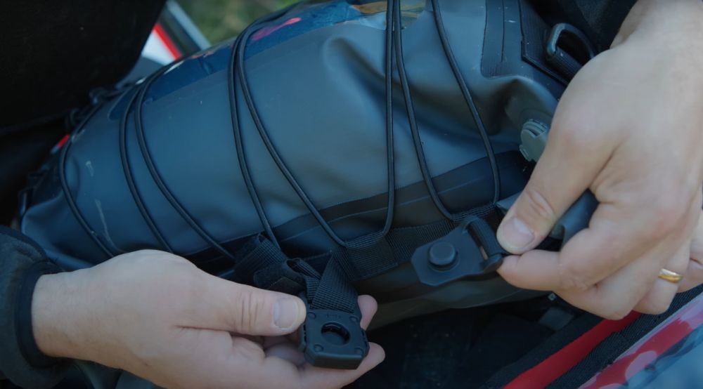 Close-up of hands snapping together Lone Rider's magnetic buckle on the duffel bag.