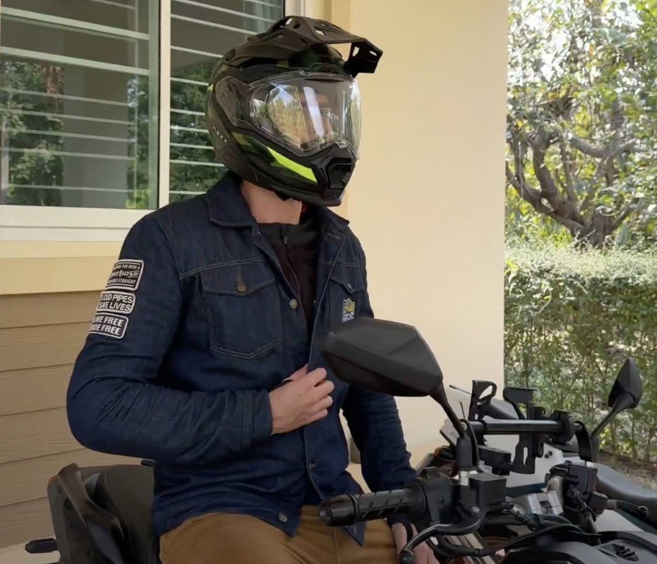 Motorcyclist wearing a denim outer jacket over protective base layers, showing how armored underlayers fit beneath casual riding gear.