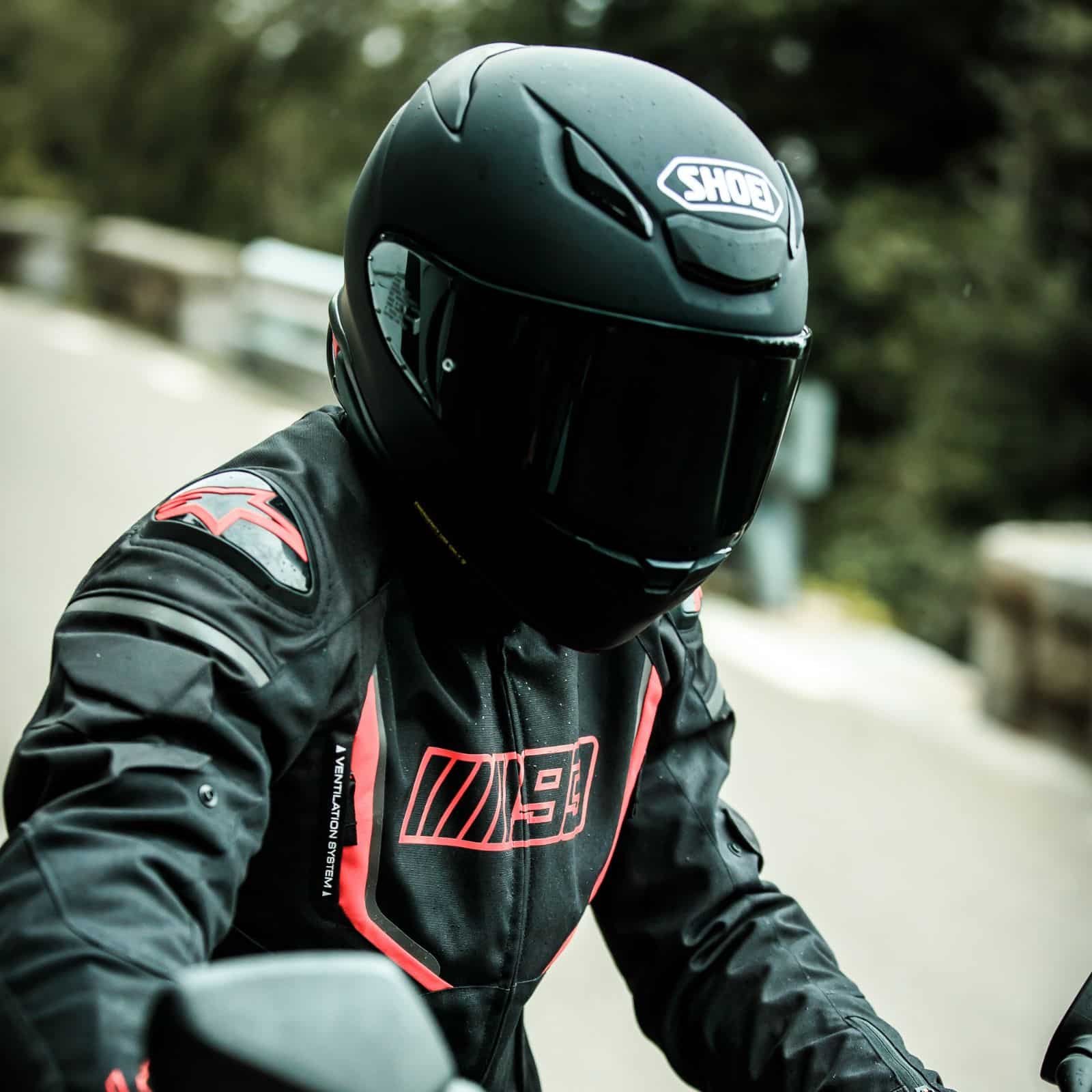 Shoei RF-1400 full-face helmet in matte black worn by rider on the road.