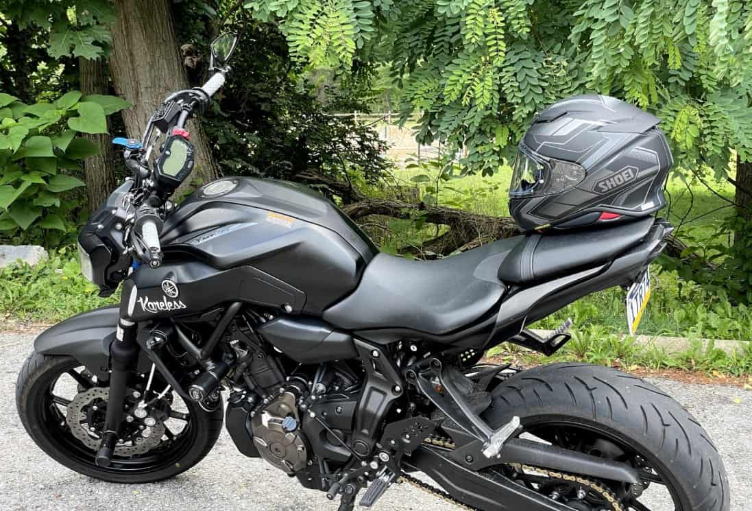 Shoei RF-1400 helmet resting on Yamaha motorcycle seat in outdoor setting