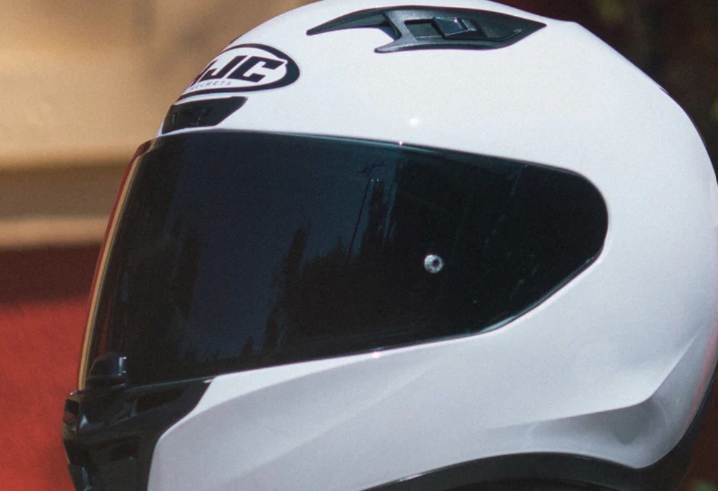 Close-up side view of HJC i10 full-face helmet in gloss white with tinted visor, showing shell design and ventilation ports.