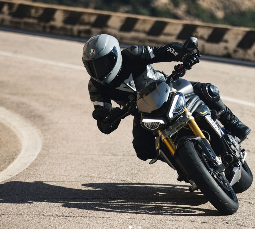 Rider cornering hard while wearing an AGV K6 S helmet, praised for light weight, wide visibility, and comfort with some wind noise trade-off.