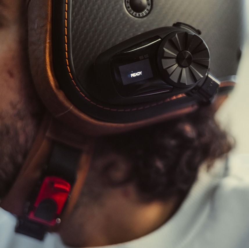 Close-up of a rider’s helmet fitted with a Sena 5S Bluetooth headset showing its LCD display.