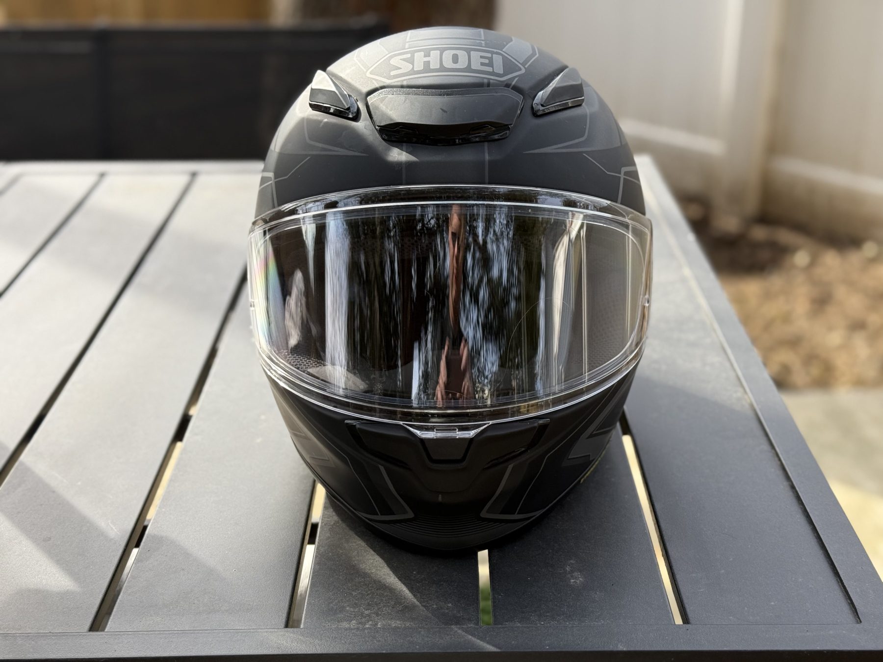 Shoei RF-1400 full-face helmet front view with clear visor on outdoor table