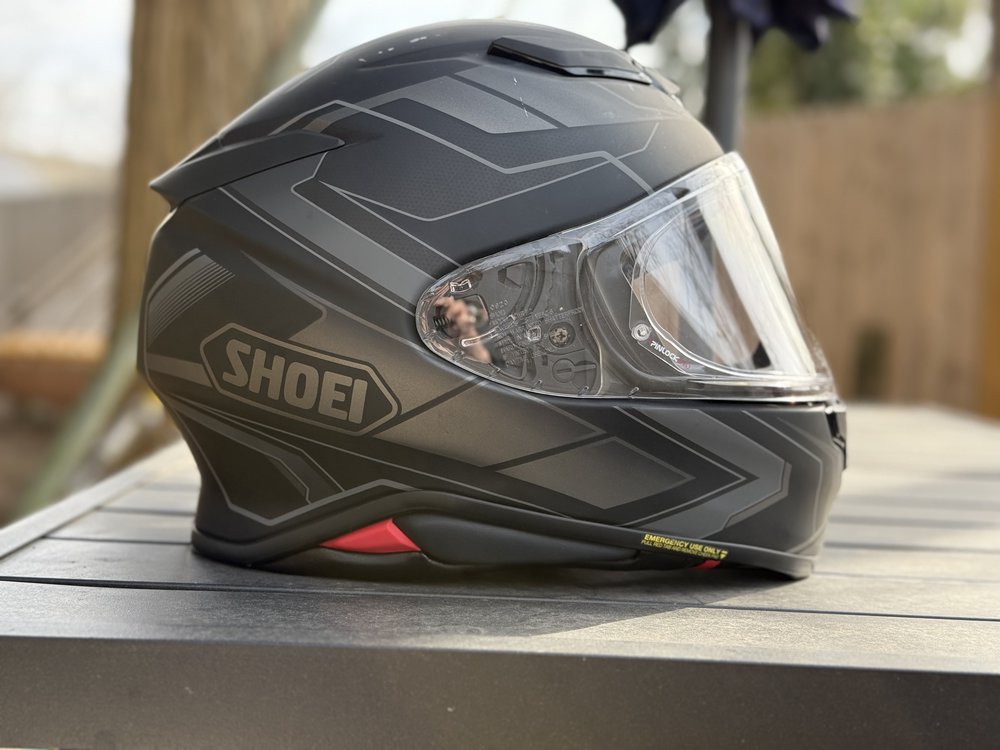 Shoei RF-1400 full-face motorcycle helmet in matte black with graphic accents, placed on an outdoor table.