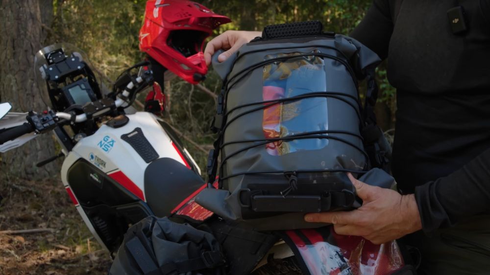 Rider holding the Lone Rider top duffel with gear inside and elastic straps wrapped around.