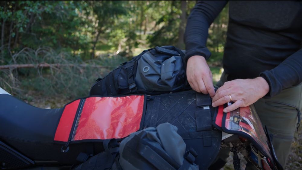 Rider adjusting straps on the Lone Rider ADV base plate with bags mounted.