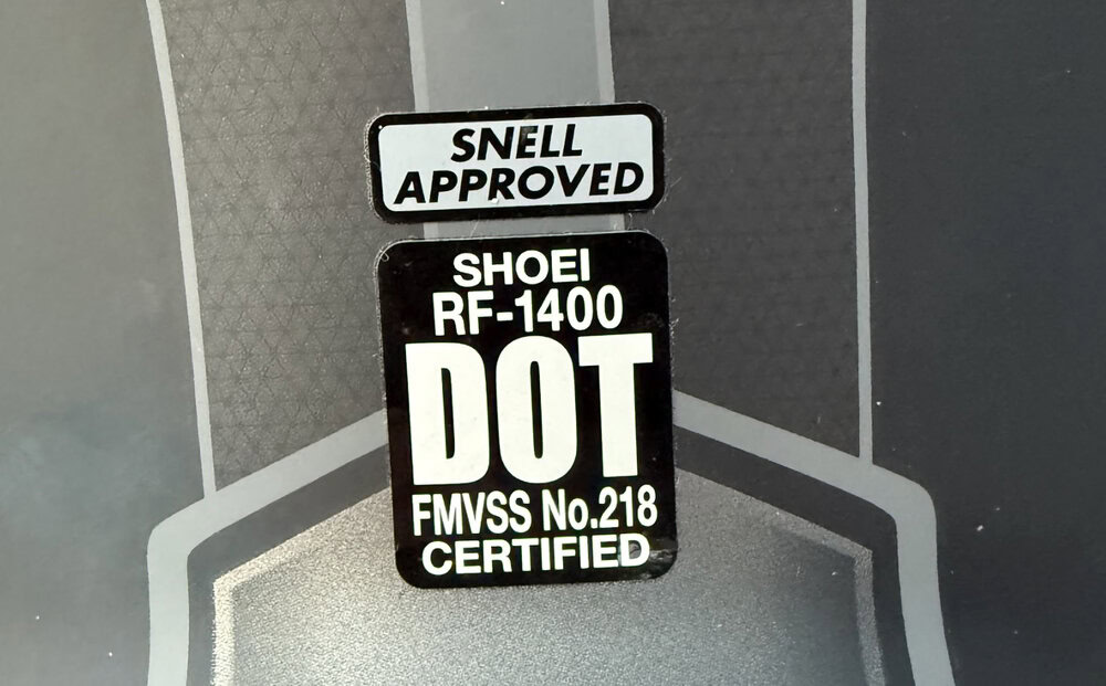 Snell and DOT certification labels on a Shoei RF-1400 motorcycle helmet.