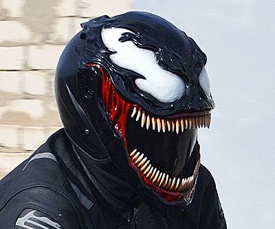 Rider wearing a sculpted, unbranded Venom-themed motorcycle helmet with exaggerated teeth and white eye decals.