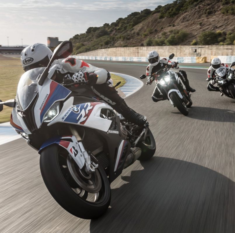 Group of sportbike riders leaning into a curve on track, highlighting performance tire handling differences