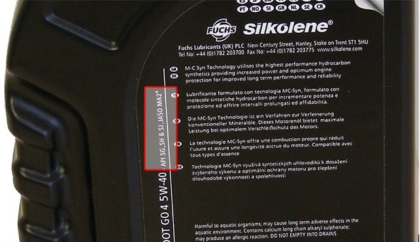 Close-up of motorcycle oil bottle label showing JASO MA2 and API certifications printed on the back label