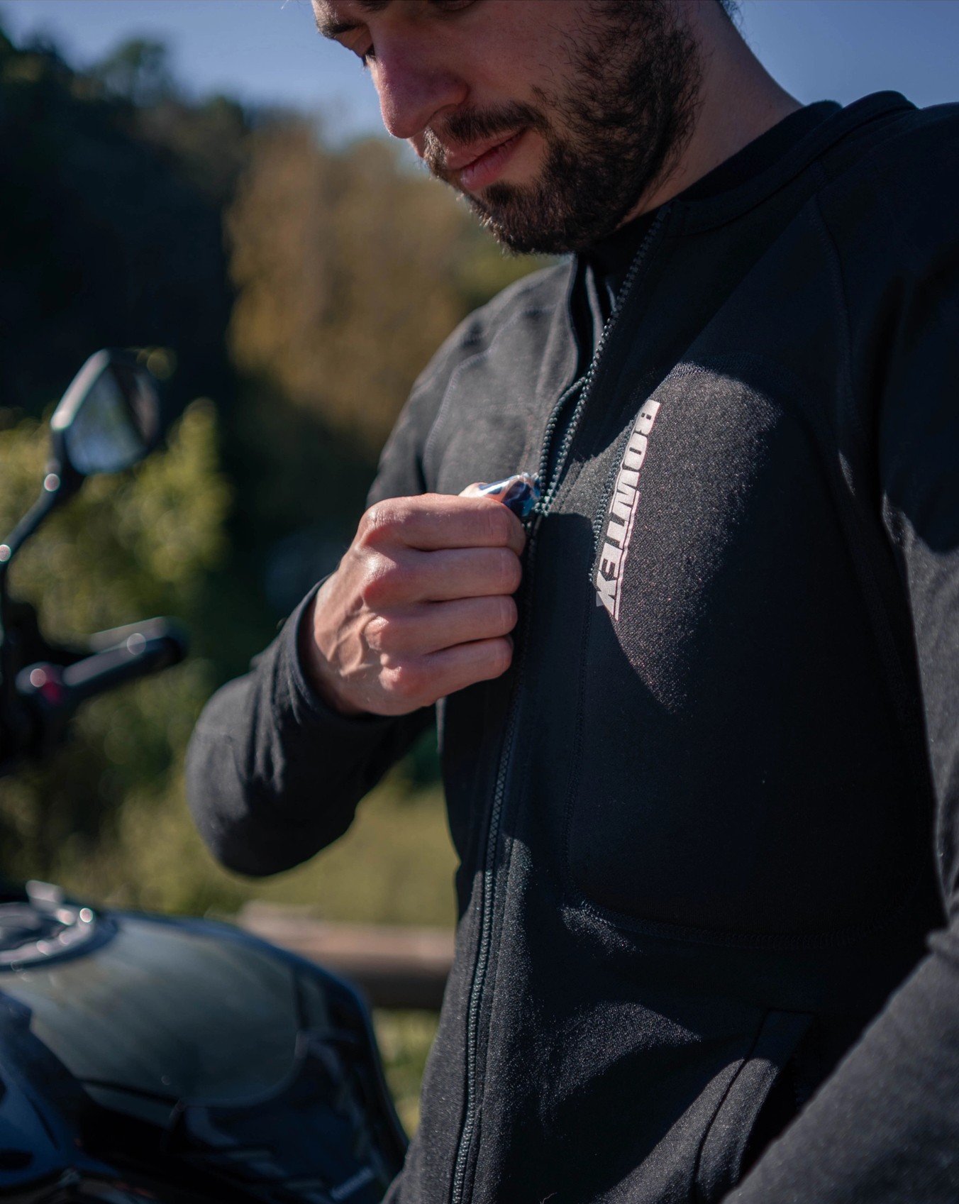 Close-up of rider zipping up a Bowtex Elite armored shirt, designed with Dyneema and Kevlar knit for abrasion resistance and breathability.