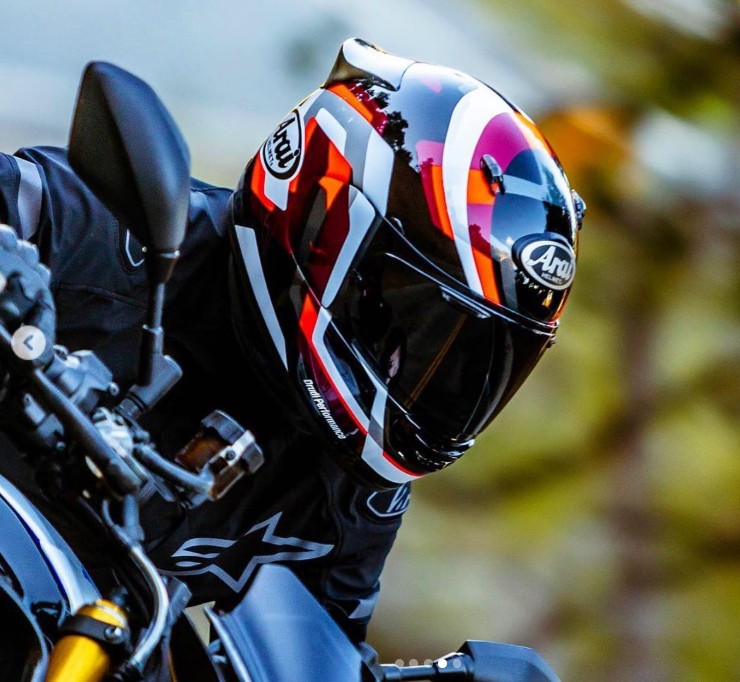 Rider wearing Arai Contour-X helmet with bold graphics, designed for airflow, stability, and quiet comfort on the road.