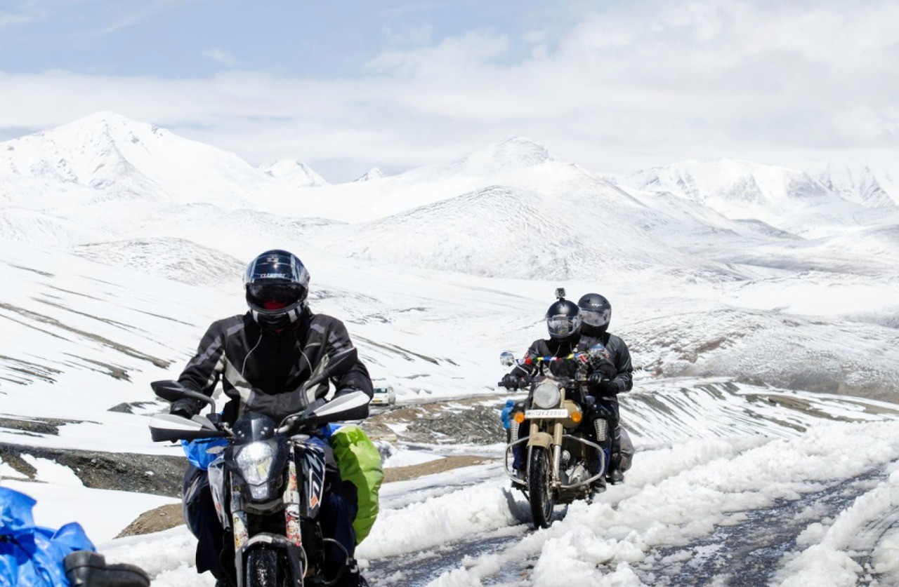 Motorcyclists riding carefully on a snowy mountain road, highlighting the importance of knowing limits in winter riding