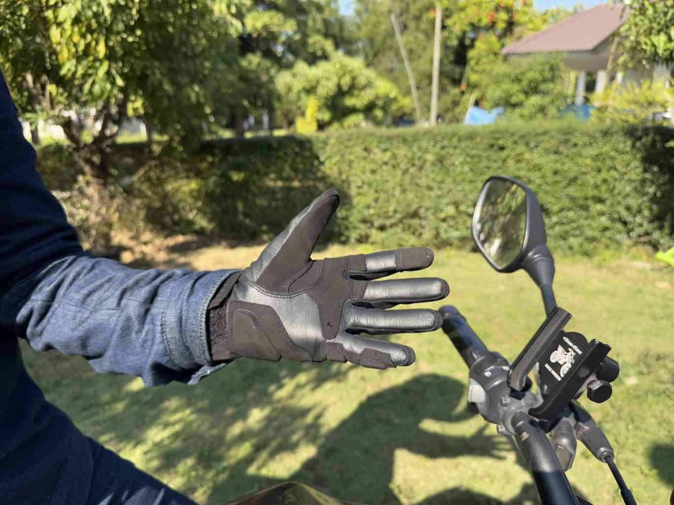 Rider wearing Alpinestars Phenom gloves resting hand on motorcycle handlebar outdoors