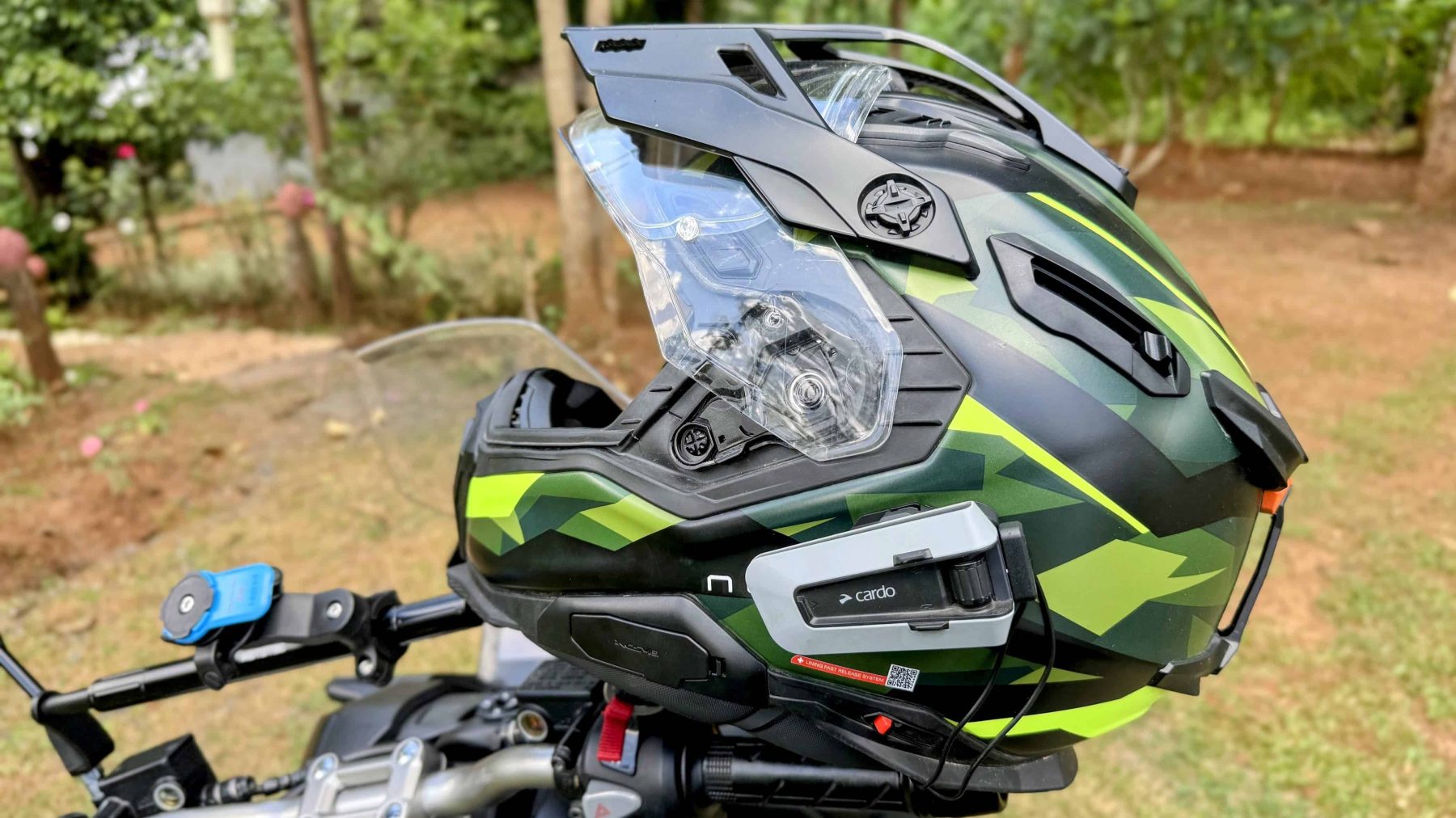 Nexx X.WED3 adventure helmet with Cardo unit mounted, shown outdoors in green camo finish