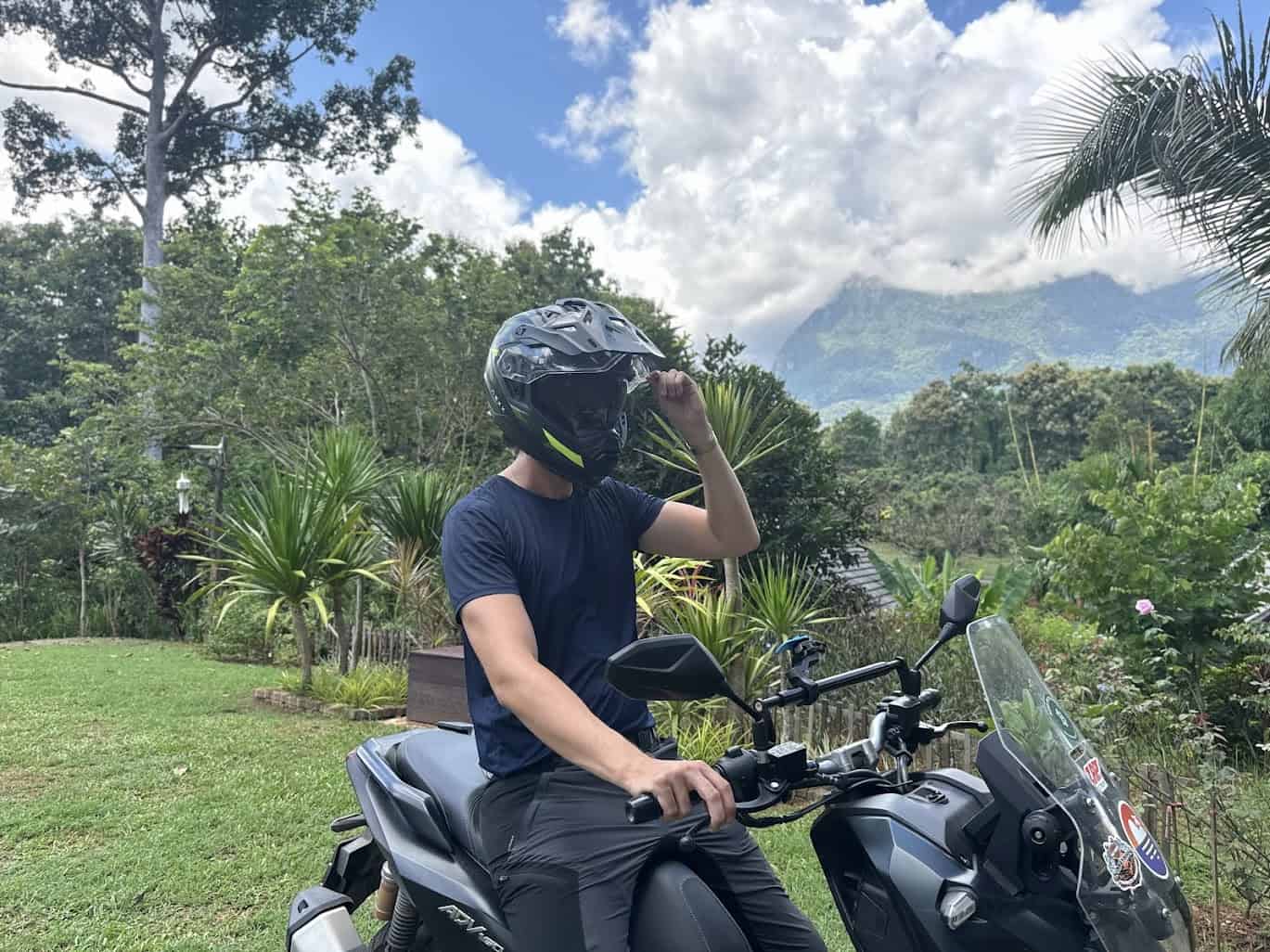 Rider wearing Nexx X.WED3 adventure helmet on scooter with mountains in the background