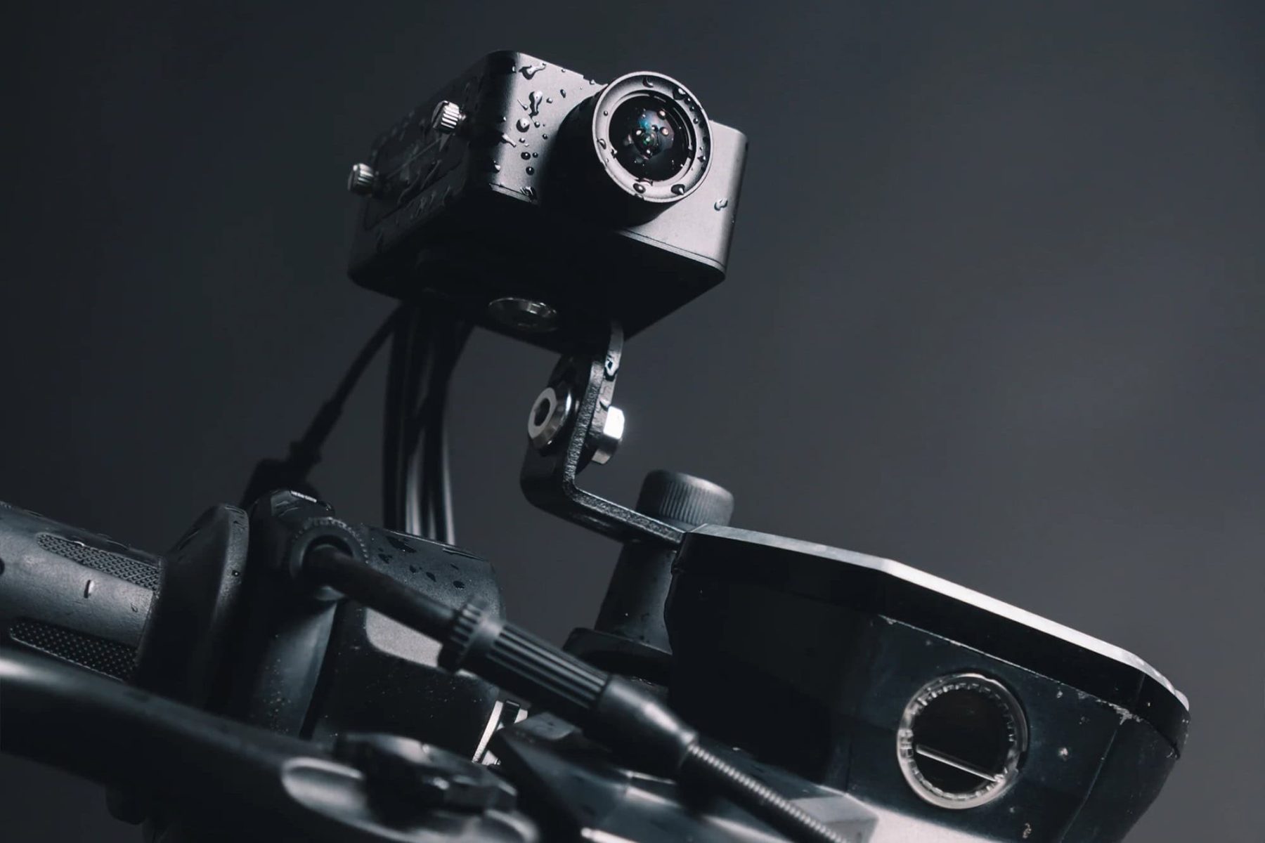 Close-up of waterproof motorcycle dash cam with water droplets on lens