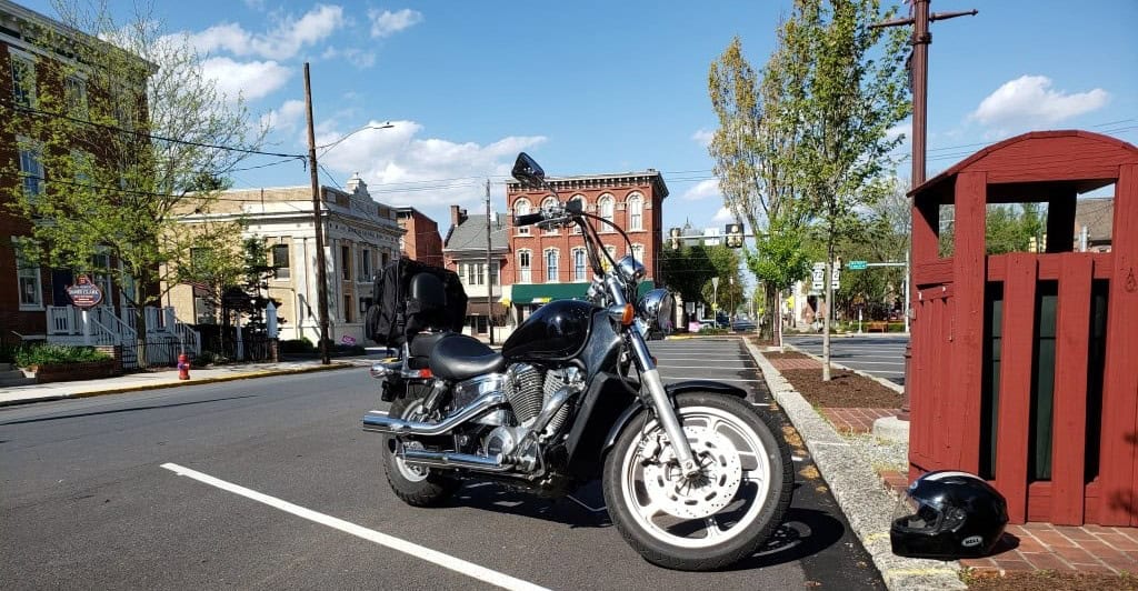 Cruiser motorcycle parked on a city street with saddlebags and helmet nearby, fitted with Kenda K671 Cruiser ST tire