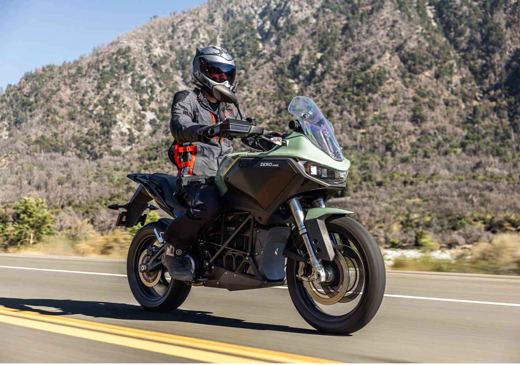Rider in Klim Latitude jacket and pants on a touring motorcycle in mountain terrain