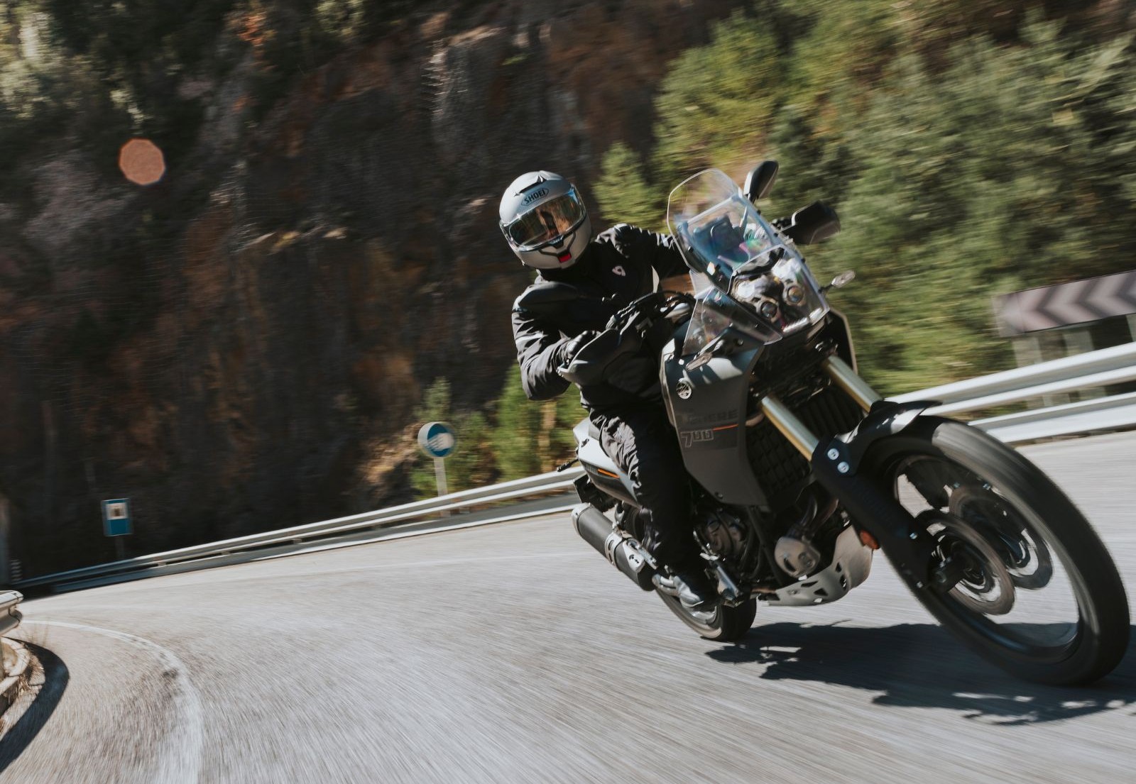 Rider wearing Shoei Neotec 3 helmet leaning into a curve on a motorcycle