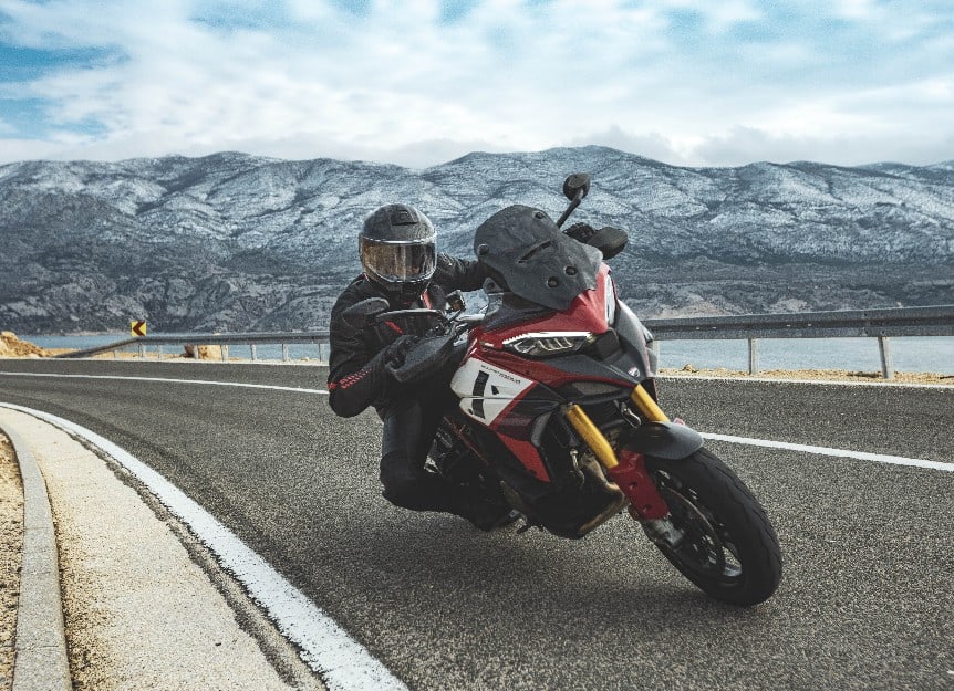 Rider leaning into a mountain curve wearing a lightweight carbon helmet