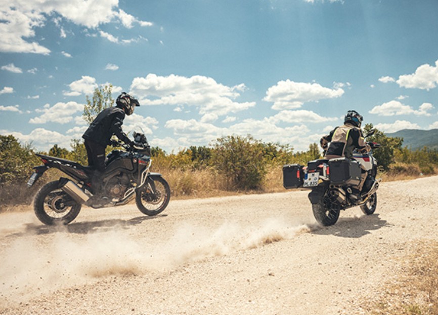 Two adventure riders on dirt road wearing Schuberth E2 helmets, showcasing stability and noise control at speed
