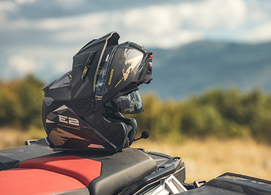 Schuberth E2 adventure modular helmet resting on motorcycle seat in outdoor setting