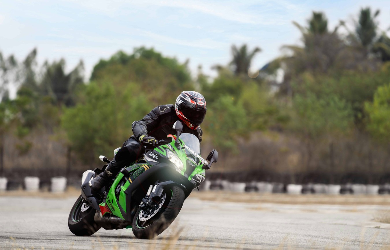 Sportbike rider leaning into a corner on a green Kawasaki Ninja, showcasing speed and control powered by Mobil 1 Racing 4T oil