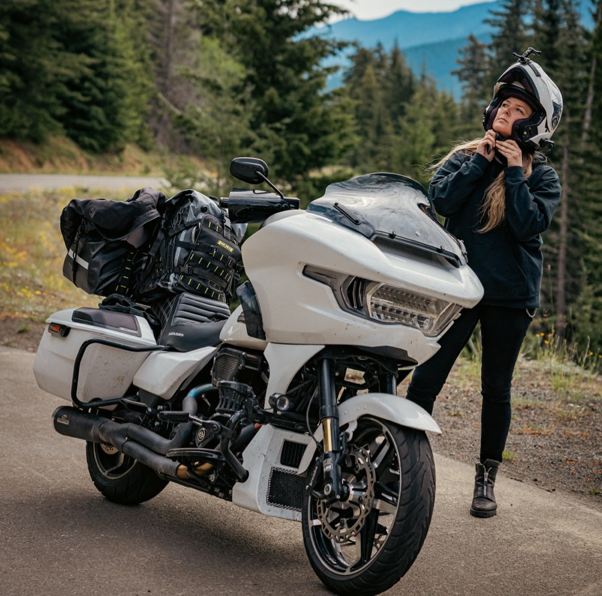 Rider adjusting a Sedici Sistema 3 modular helmet beside a touring bike in the mountains